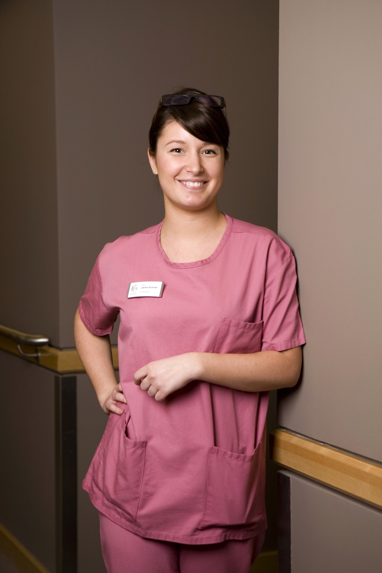 Janine Schulze, a medical assistant at Berlin's Meoclinic, wearing pink medical scrubs and a name badge.