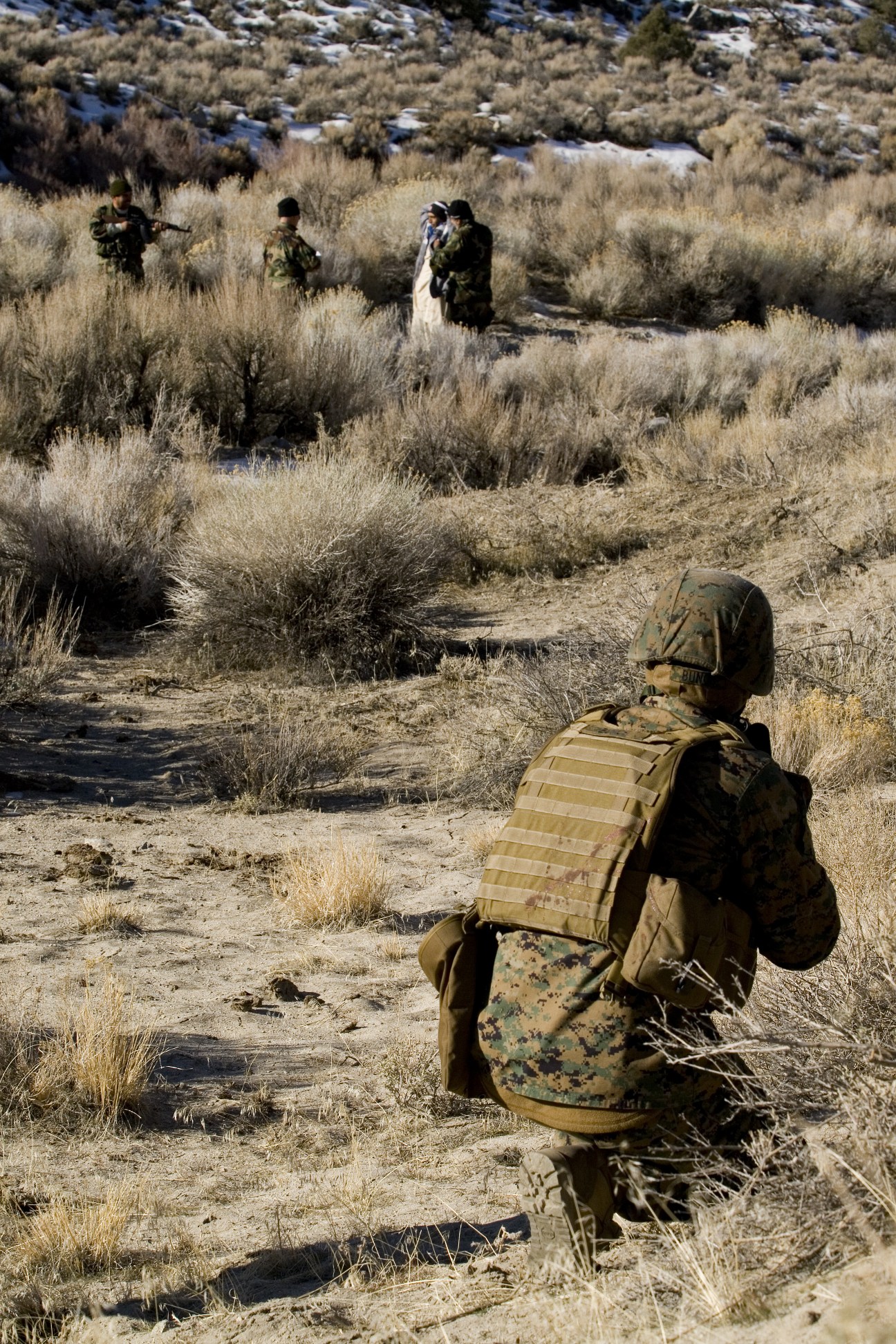 Marine in camouflage confronts an Afghan role player approaching base camp during Mountain Viper training exercise in Nevada.