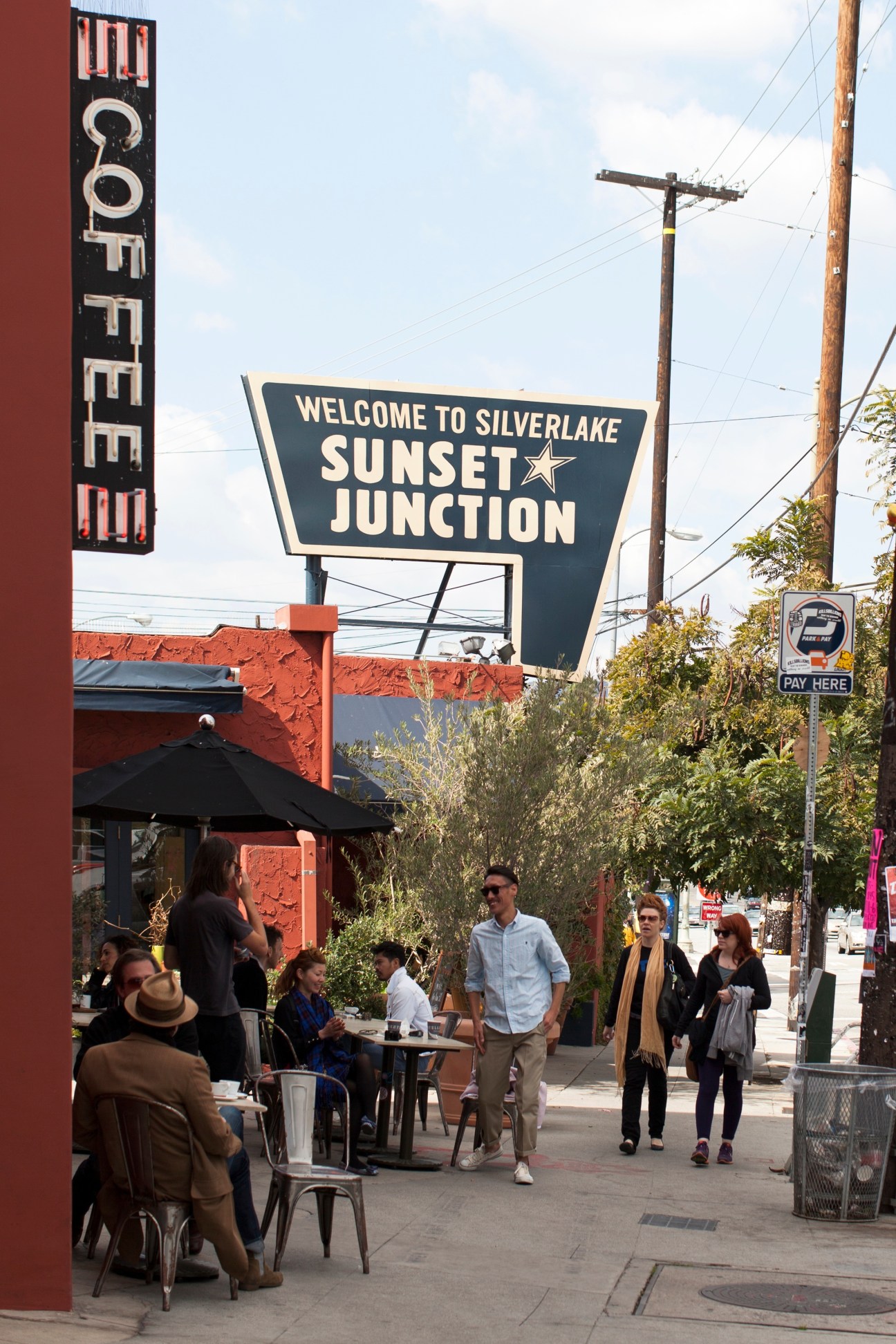 People gather outside Intelligentsia Coffee at Sunset Junction in Silver Lake, with a vintage neon sign visible.