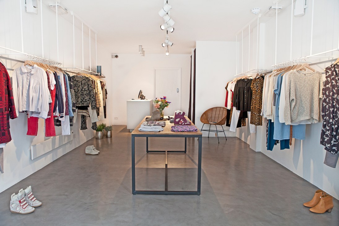 Interior of Aimé boutique on Redchurch Street with clothing racks and central display table.