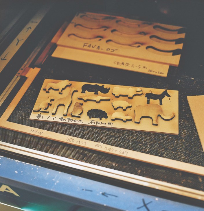 Cedar wood toy templates with animal shapes and Japanese markings laid on a workshop surface.
