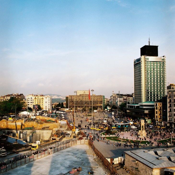 Aerial view of Taksim Square in Istanbul showing construction sites, crowds, and surrounding buildings during redevelopment.