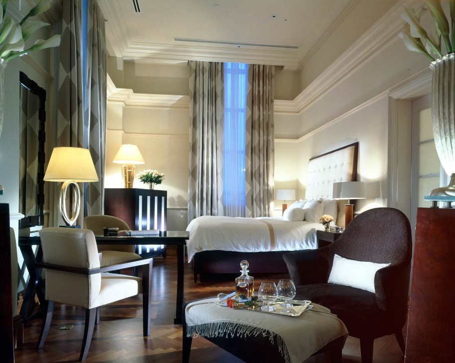 Luxurious hotel bedroom at The Fullerton Hotel, Singapore, with contemporary furnishings and elegant lighting.