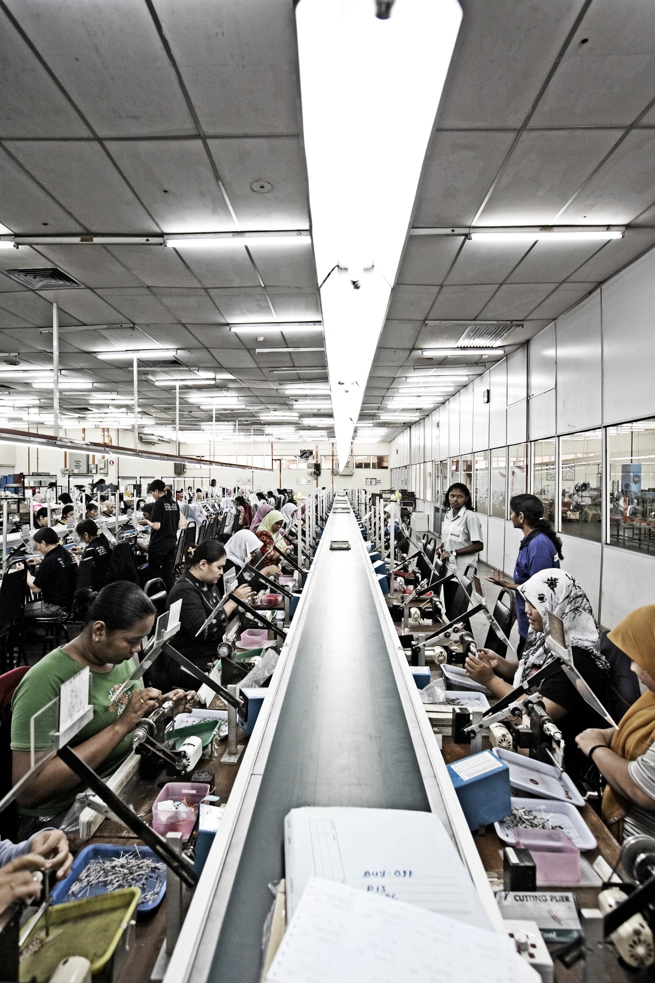 Workers assemble electronics on a long production line at Fastron manufacturing facility in Penang.