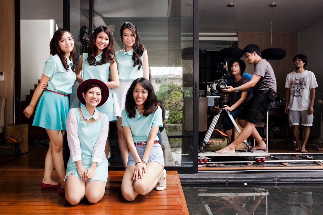 Apple Girls Band members in aquamarine outfits posing during an advertisement film shoot.