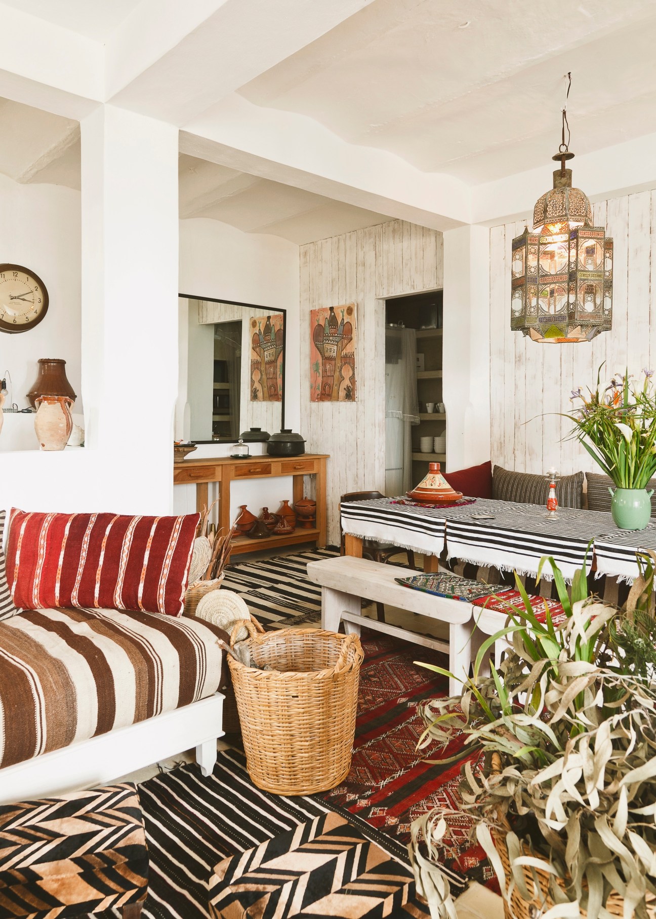 A bright living room with striped furniture, Moroccan lantern, and eclectic décor in the Neguedes' Tangier home.