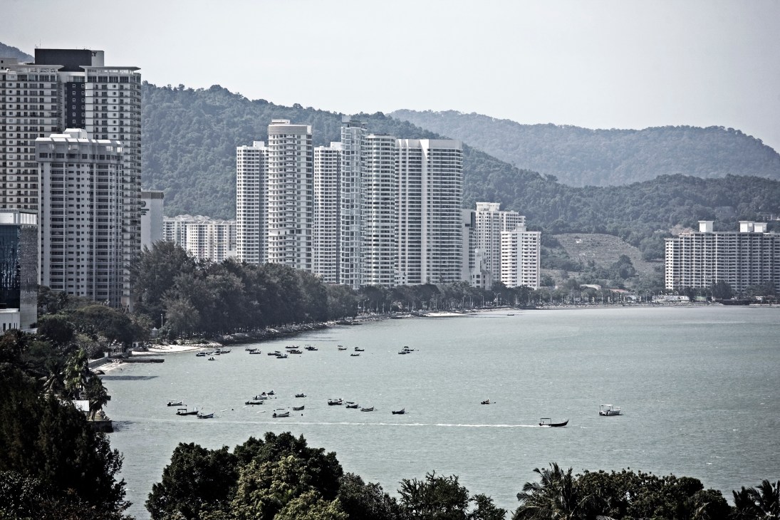 Waterfront condominiums with forested hills behind in George Town, Penang.