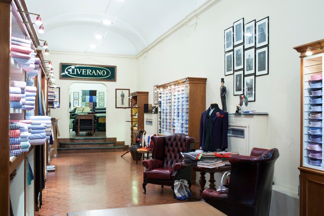 Interior of Liverano & Liverano tailor shop in Florence with fabric swatches and finished suits on display.