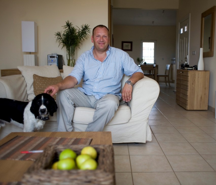 Justin Crowther, resort director at Sambala Village, sits in a modern villa with a dog beside him.