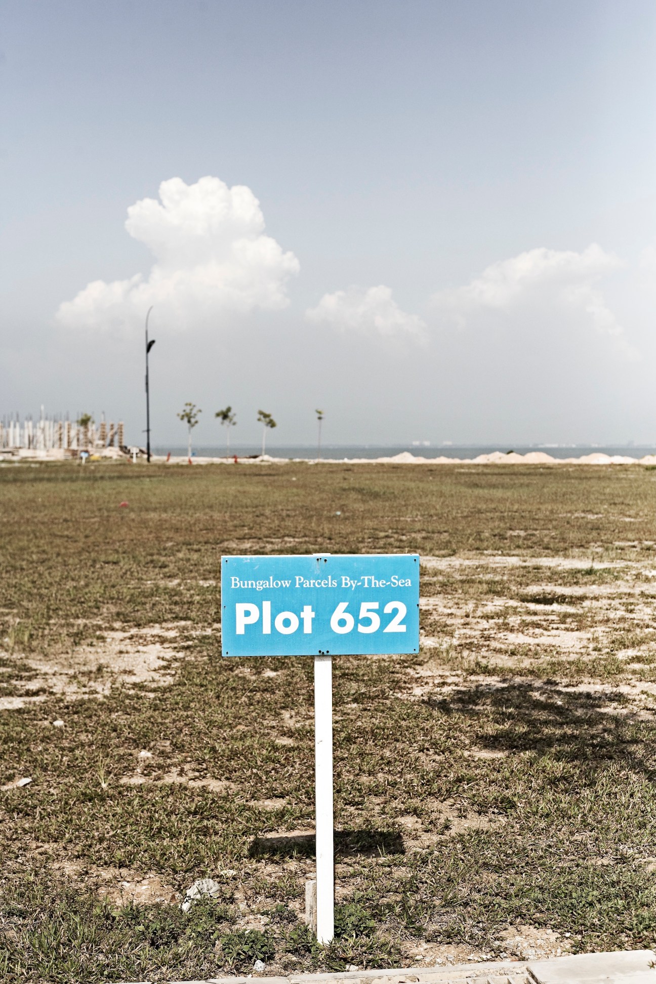 A blue sign marking Plot 652 of Bungalow Parcels By-The-Sea on undeveloped land on George Town's western fringe.
