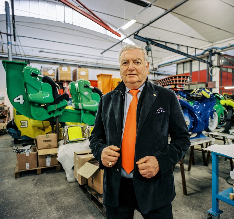 CEO Alberto Zamperla stands in the Zamperla factory among colorful ride components and machinery.