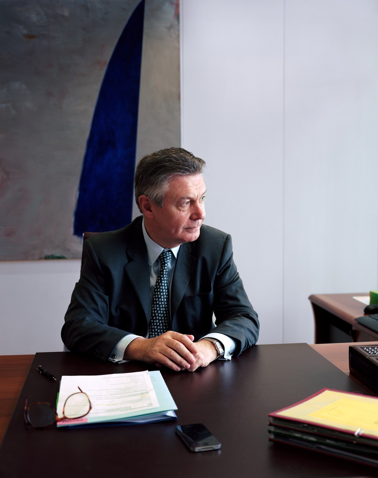 Karel De Gucht, European Commission Trade Commissioner, seated at desk in Brussels office with documents and modern art in background.