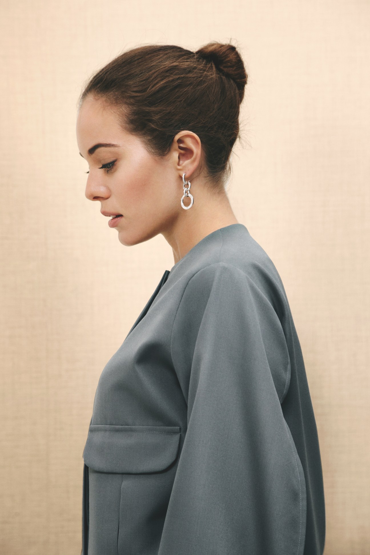 Woman wearing a grey top by Dušan with silver drop earrings by Cartier, shown in profile.