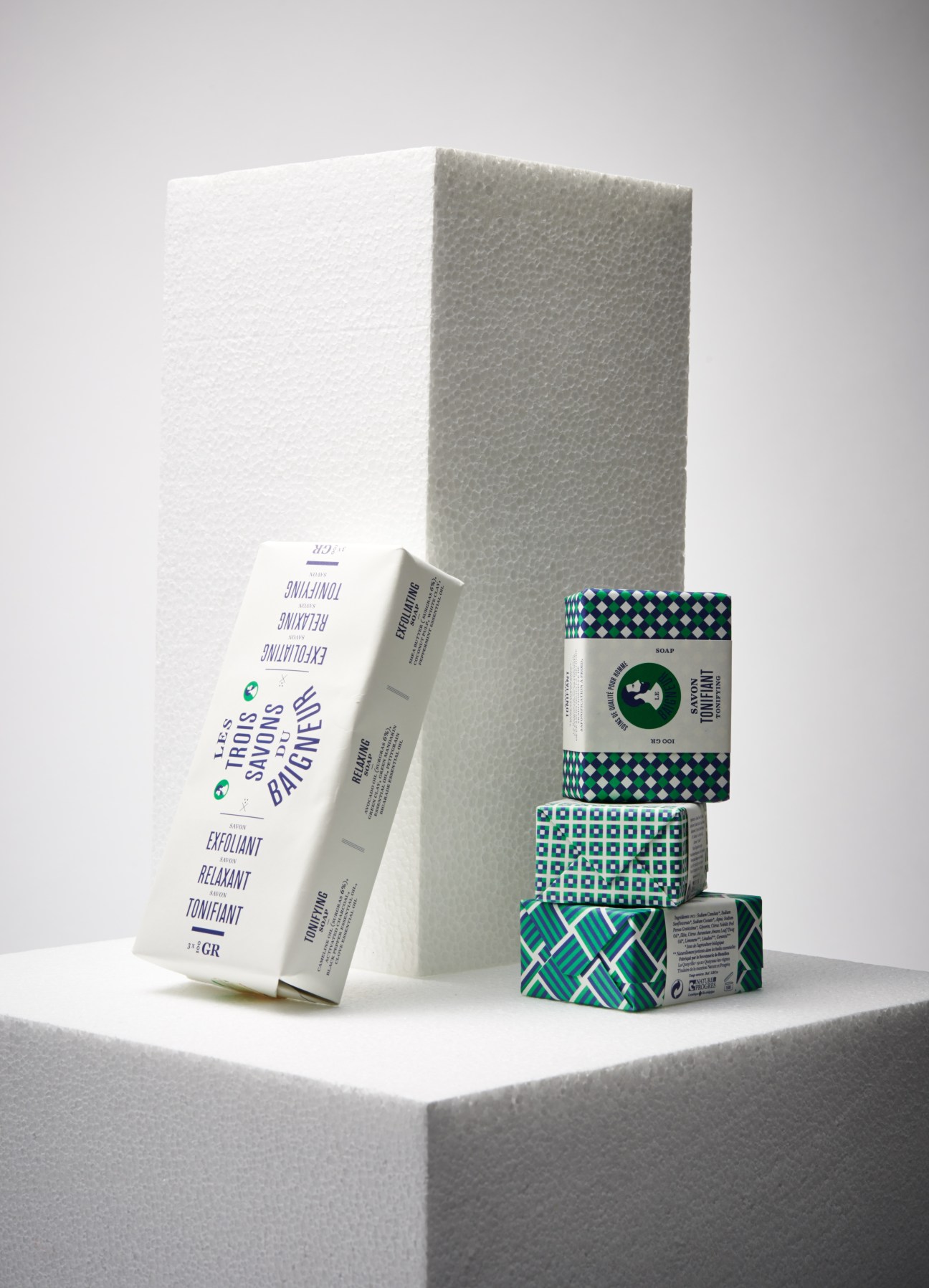 Le Baigneur organic soaps in geometric patterned packaging displayed on white cube.