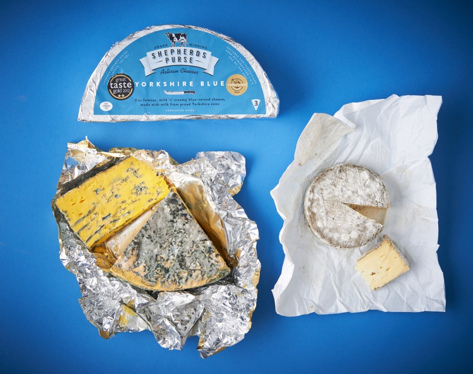 Shepherds Purse cheeses displayed on a blue background, including wrapped Yorkshire Blue and unwrapped varieties.