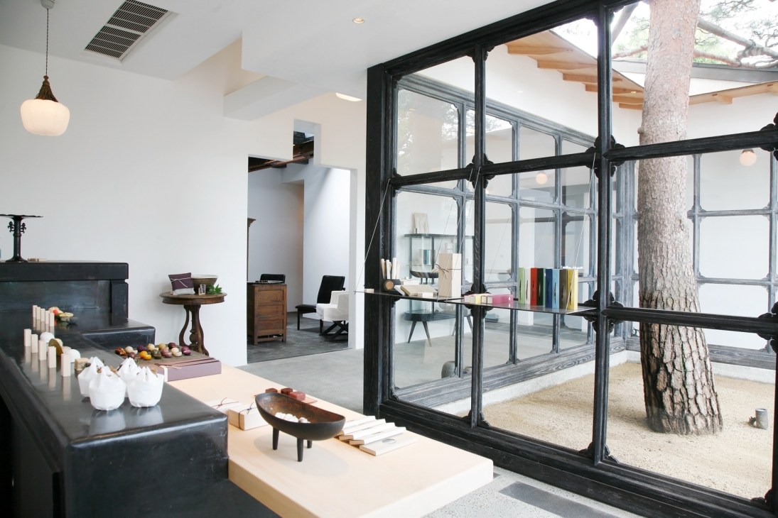 Modern interior of Baishinka café in Tokyo with fireplace, large black-framed windows and natural light.