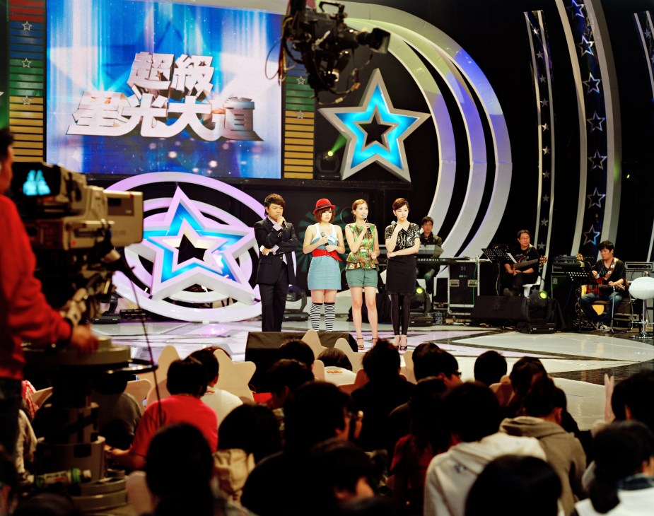 Contestants perform on the stage of One Million Star, a Taiwanese pop talent show, with an illuminated star logo and Chinese characters displayed on the backdrop.