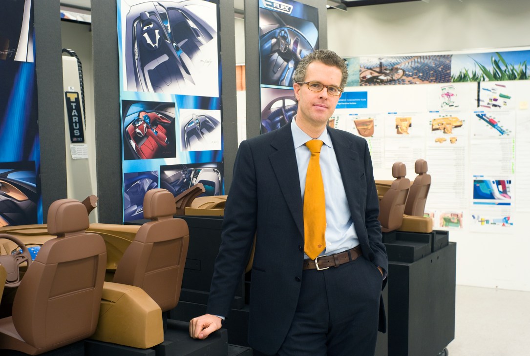 Frank Weber stands in a design studio with Chevrolet Volt interior mockups and sketches displayed behind him.