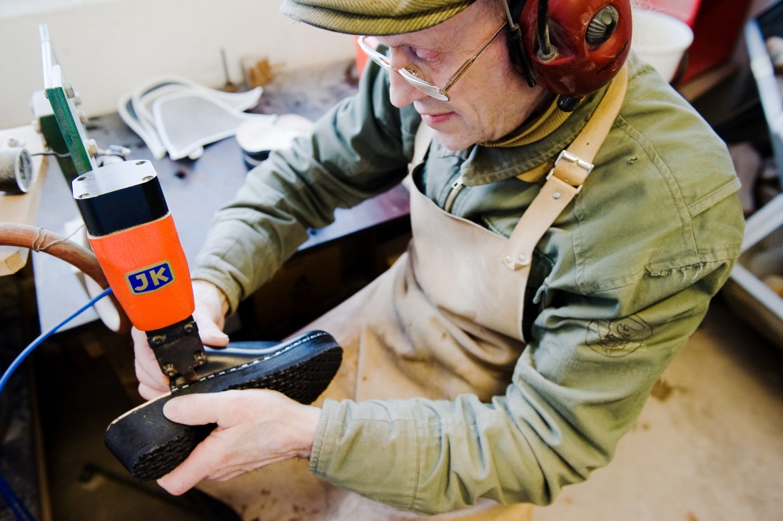 Paavo Puotila applies adhesive to a wooden clog sole in the Talla workshop.