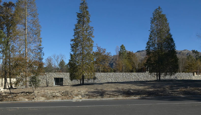 Low-lying granite building with dark entrance nestled among tall trees in a national park landscape.
