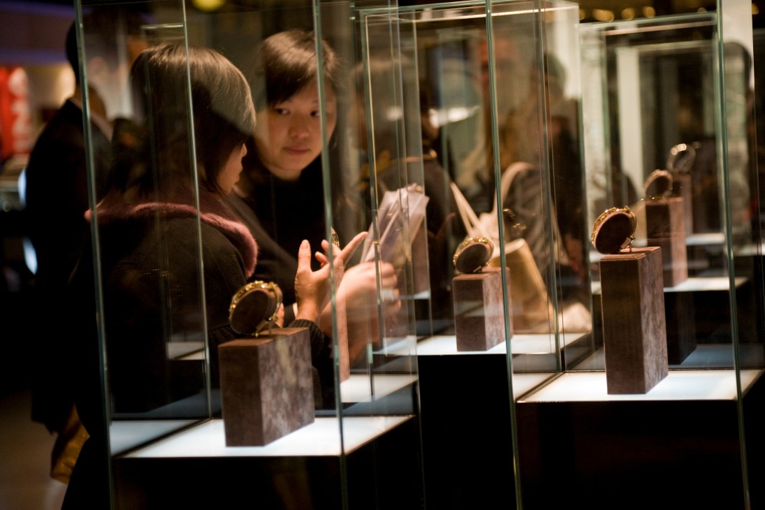 Visitors view luxury watches displayed in glass cases at the Gucci booth.