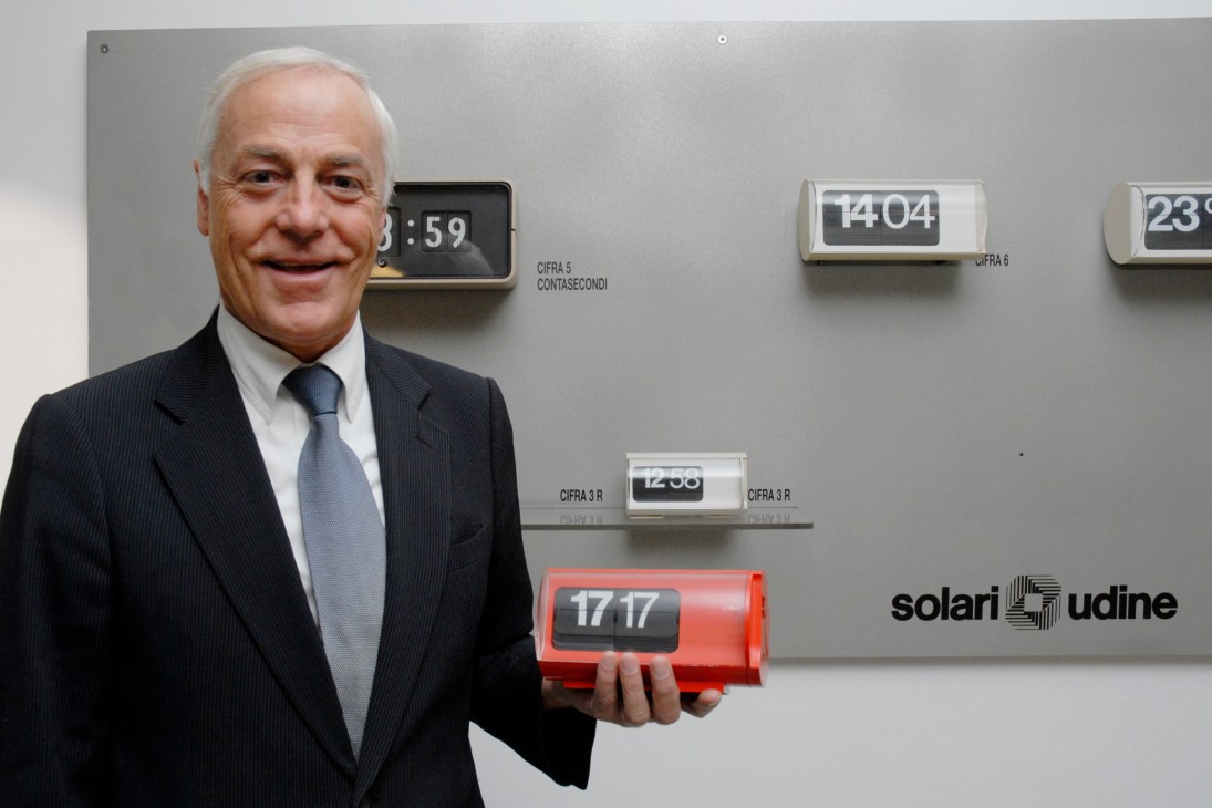 Solari president Massimo Paniccia holds a red Cifra 3 flip clock displaying 17:17