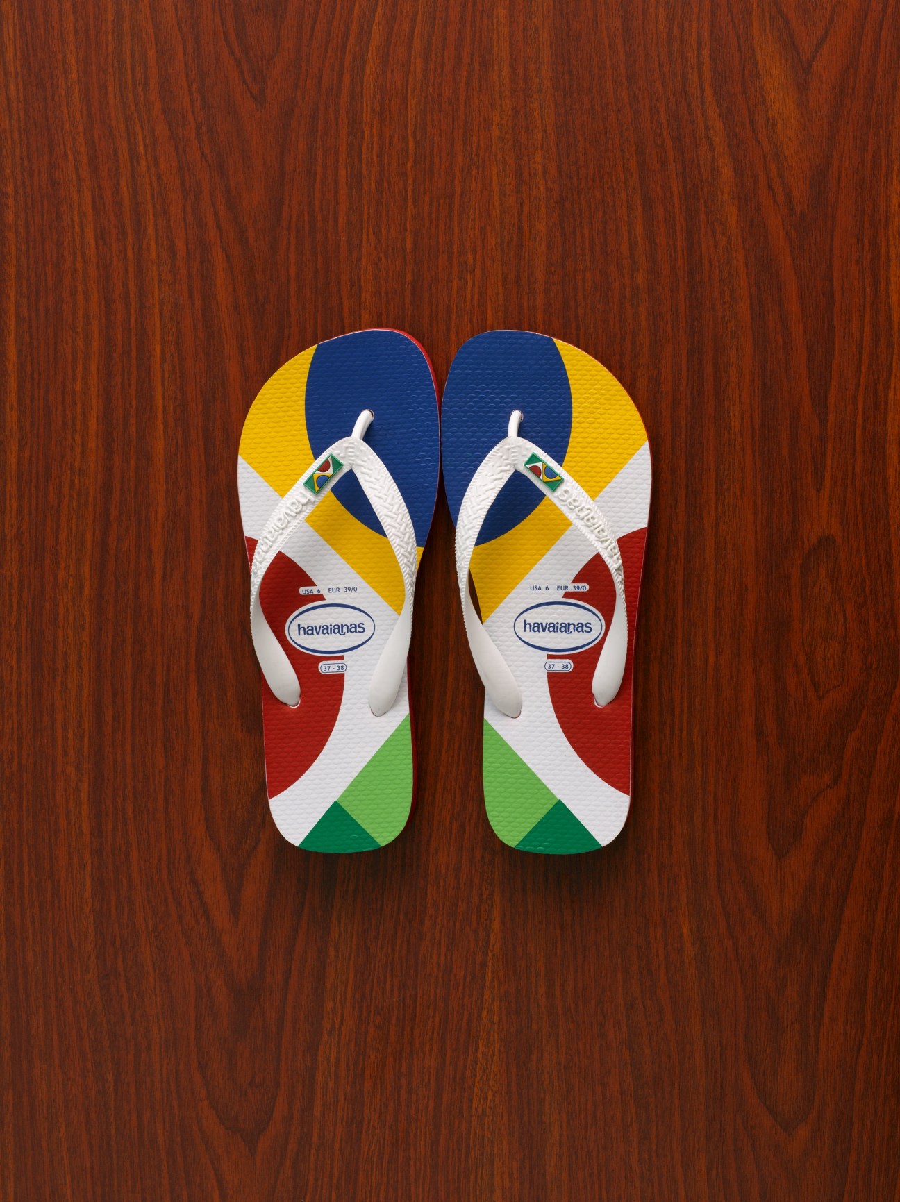 Pair of Havaianas flip-flops with Japanese flag colors on wooden background.