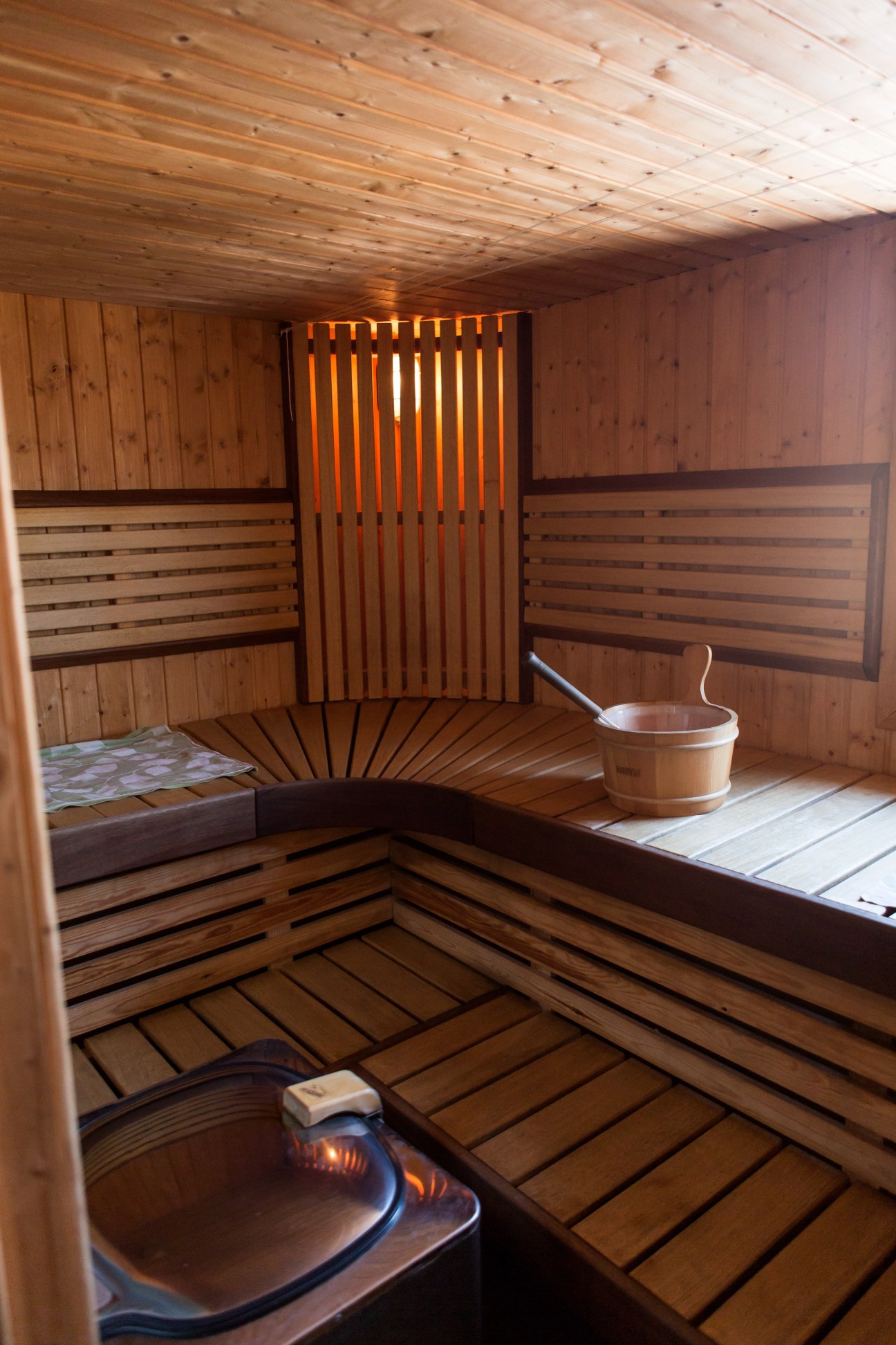 Interior of a traditional Finnish sauna with wooden benches, heating stove, and bucket.