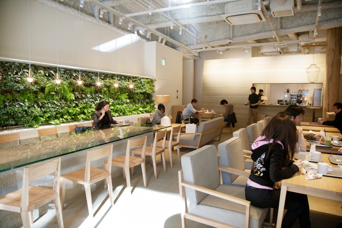 Interior of The 3rd Burger restaurant showing wooden seating, green living wall, counter, and customers dining.