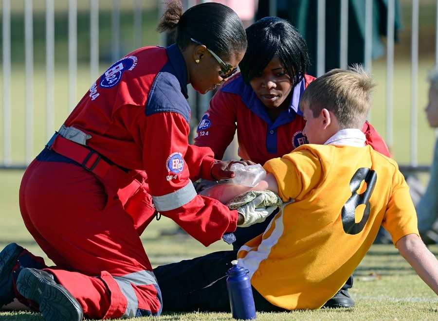 Paramedics in red uniforms providing emergency medical care to a young patient.