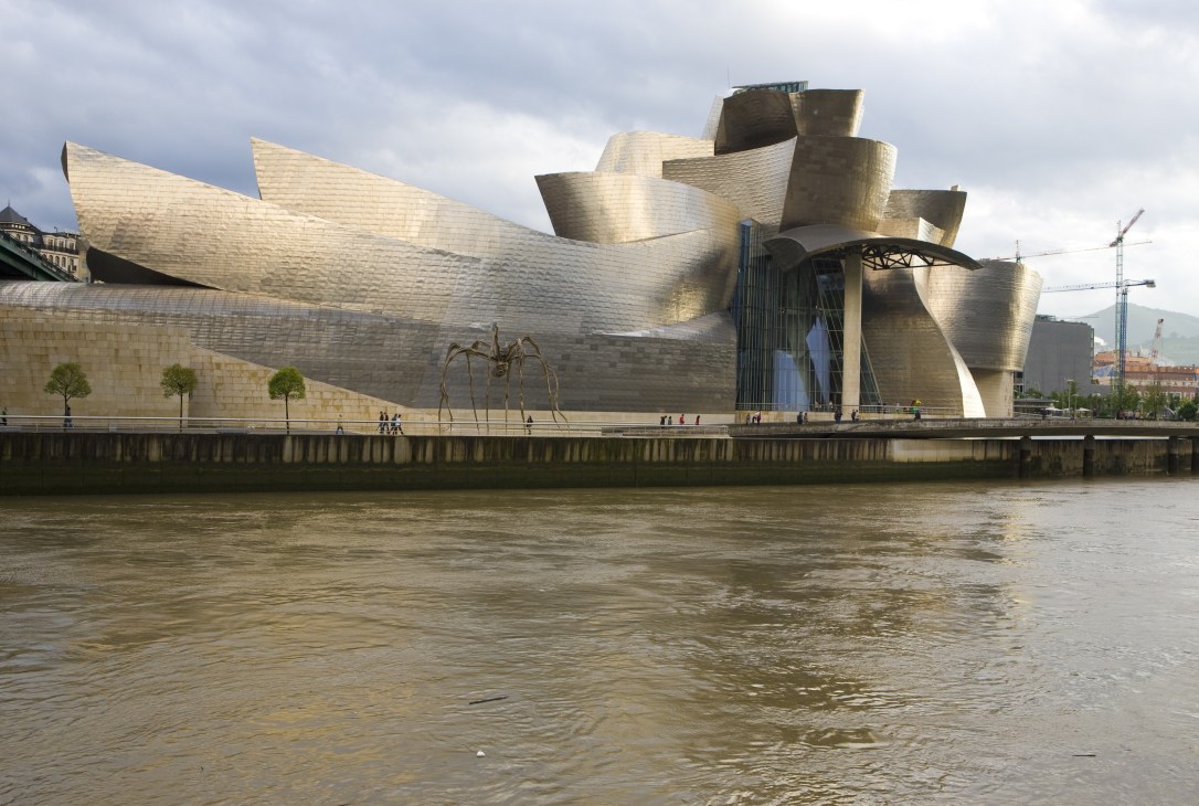 The Guggenheim Museum's distinctive curved titanium structure reflected in the Ría de Bilbao river.