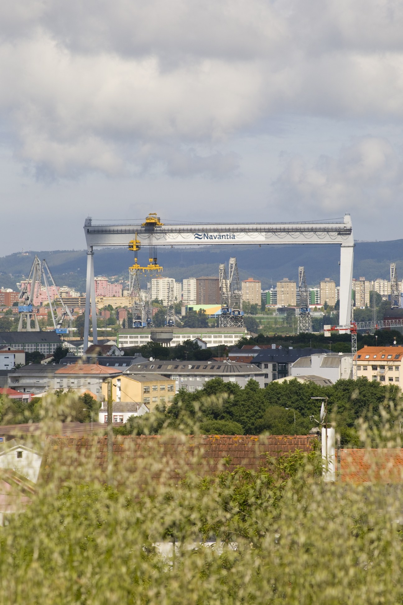 Navantia shipyard gantry crane spanning the water with Spanish city in background.
