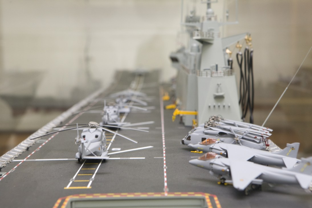 Detailed scale model of a naval aircraft carrier flight deck with helicopters and fighter jets.