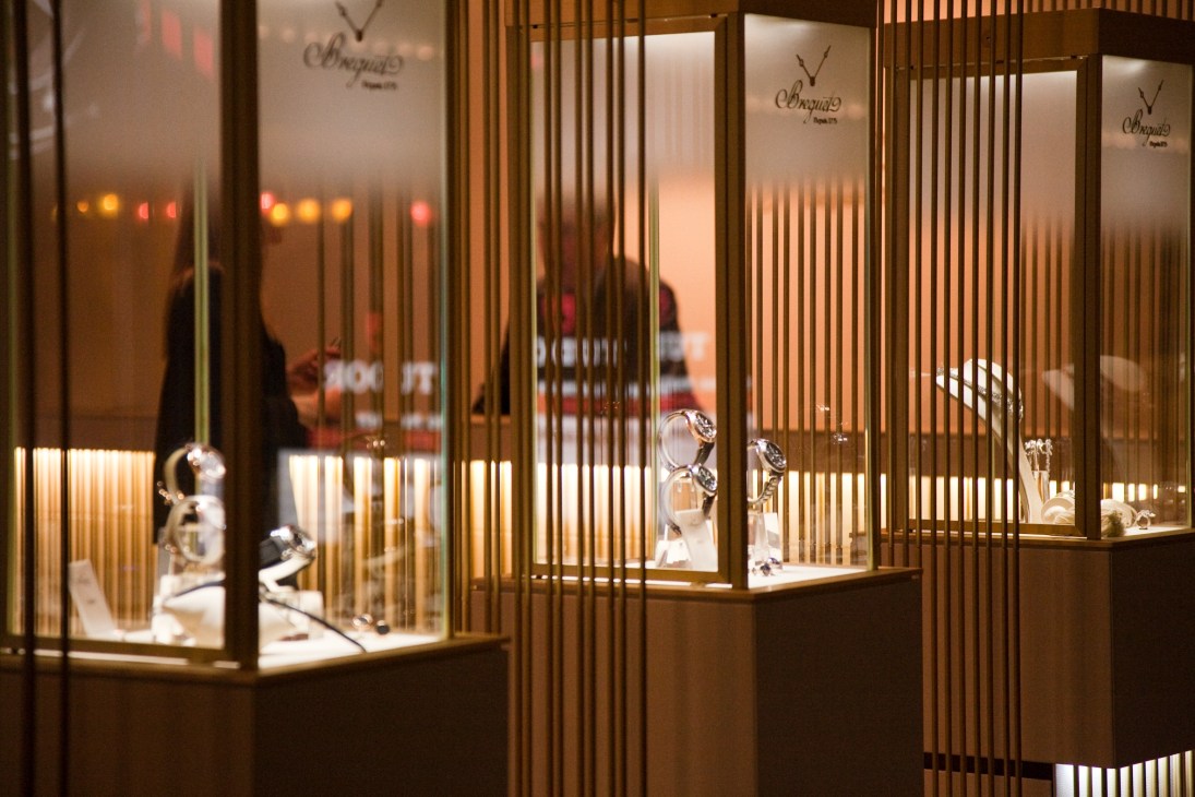 Breguet's exhibition stand with illuminated display cases featuring watches behind vertical brass dividers.