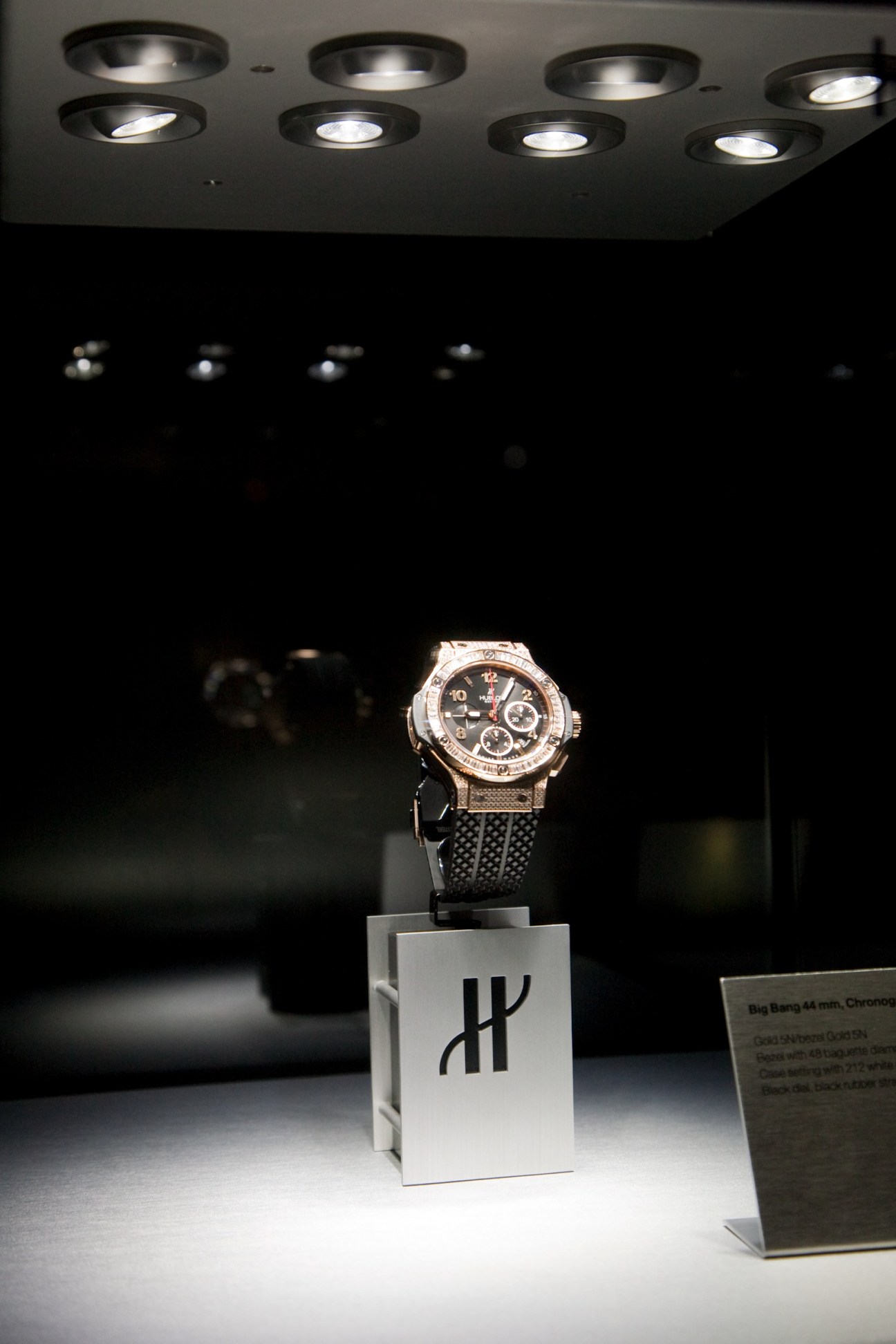 Hublot's Big Bang 44mm chronograph watch displayed on a white stand under gallery lighting.