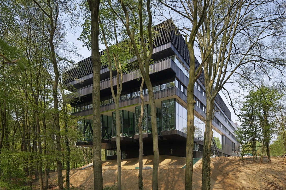 Modern multi-story rehabilitation centre with anodised-aluminium façade nestled among forest trees.