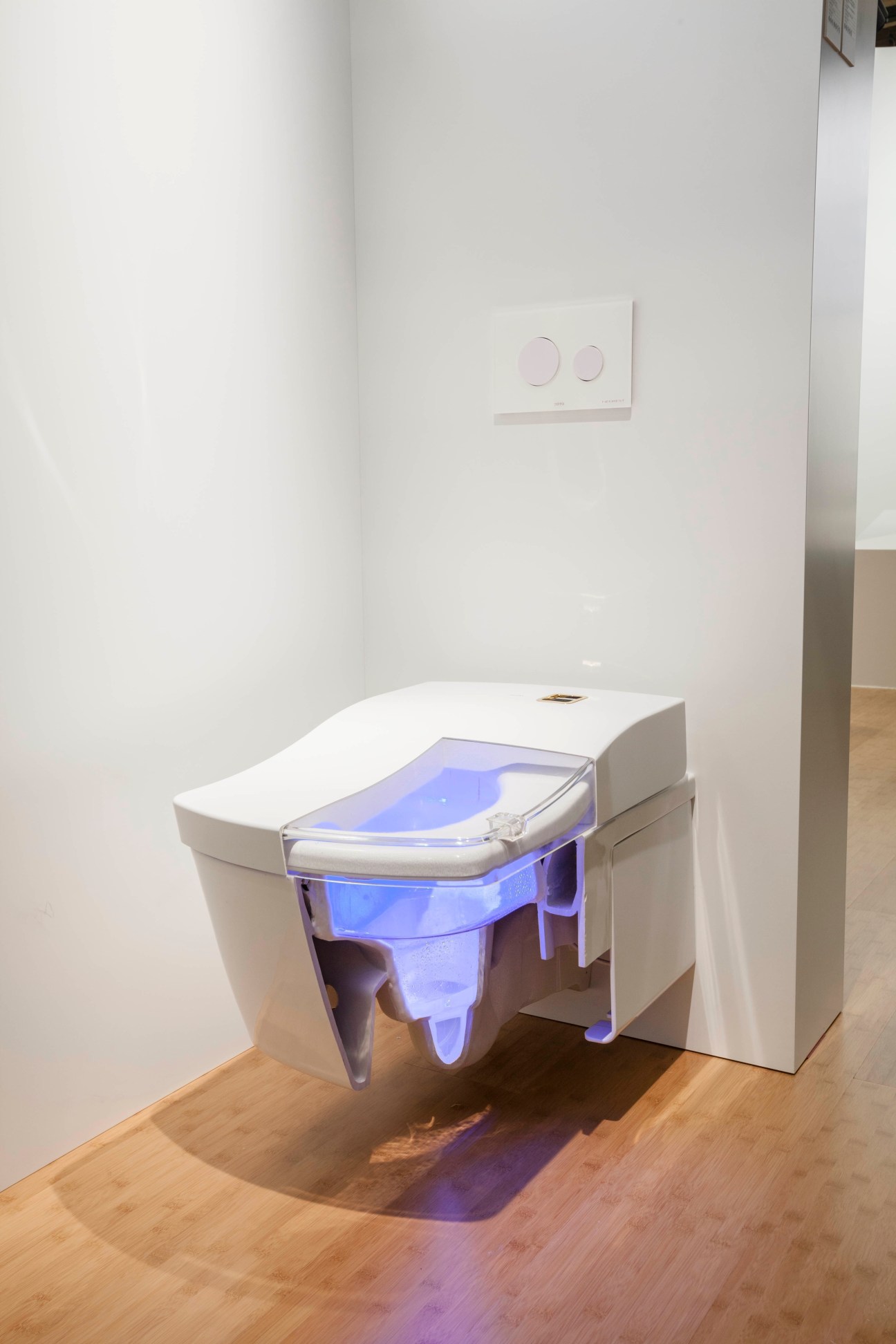 TOTO's new self-cleaning washlet toilet with blue-lit interior on wooden floor.