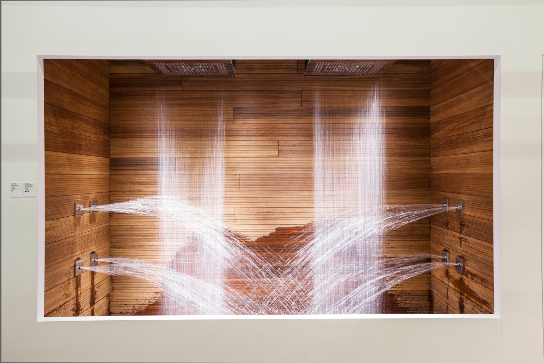 TOTO's latest shower system displaying multiple water jets from ceiling and wall-mounted heads in a wooden-walled bathroom.
