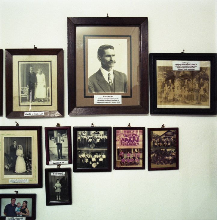 Framed black and white photographs of early Pomeranian settlers displayed on a white wall.