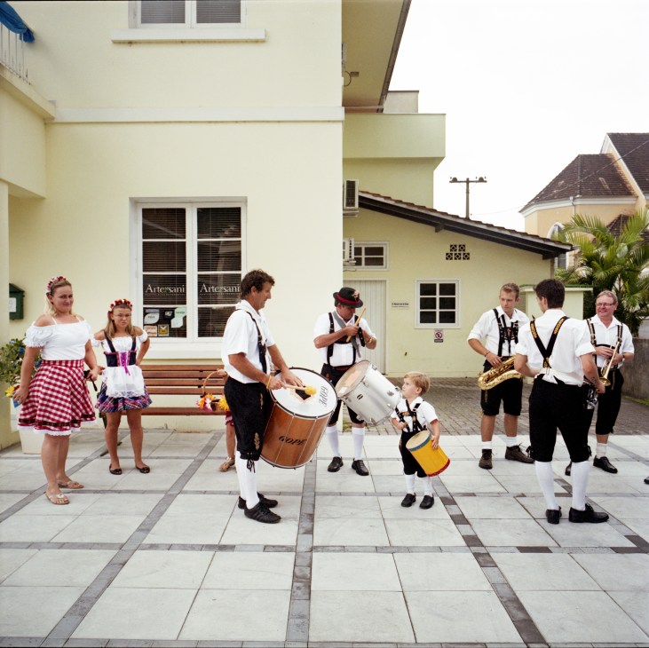 Musicians and performers in traditional German Dirndl and Lederhosen prepare for a festival parade in Pomerode.