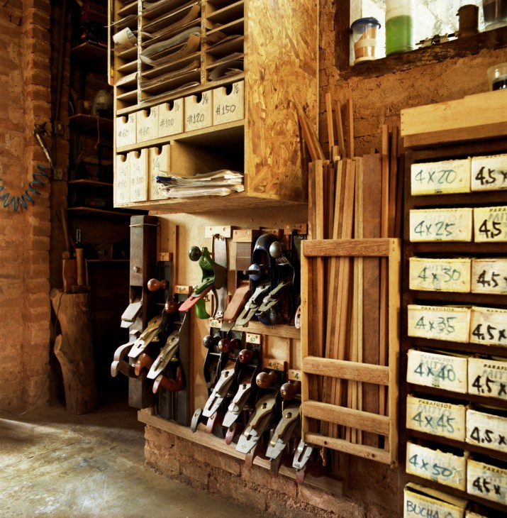 Carpentry workshop with hand planes and woodworking tools organized on walls and shelves.