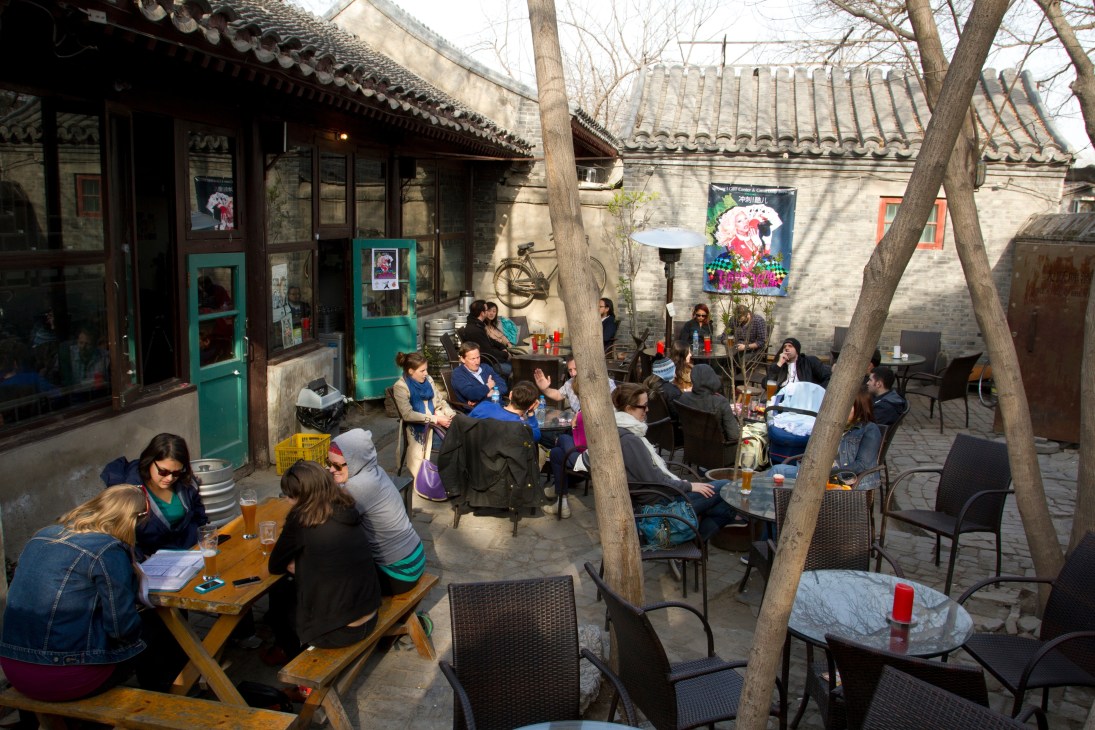 Outdoor courtyard at Great Leap Brewery in Beijing with visitors seated at tables under traditional Chinese architecture.