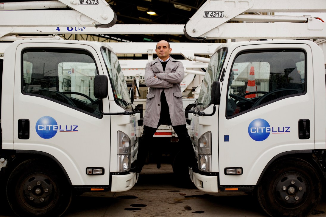 Gerardo Ramírez, general manager of Citeluz, stands between two white service vehicles with the company logo.
