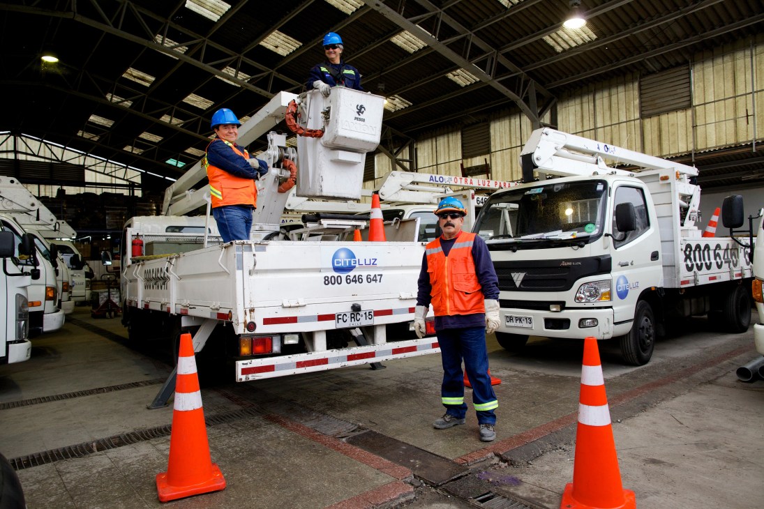 Citeluz maintenance crew with cherry picker and utility trucks in Santiago warehouse.