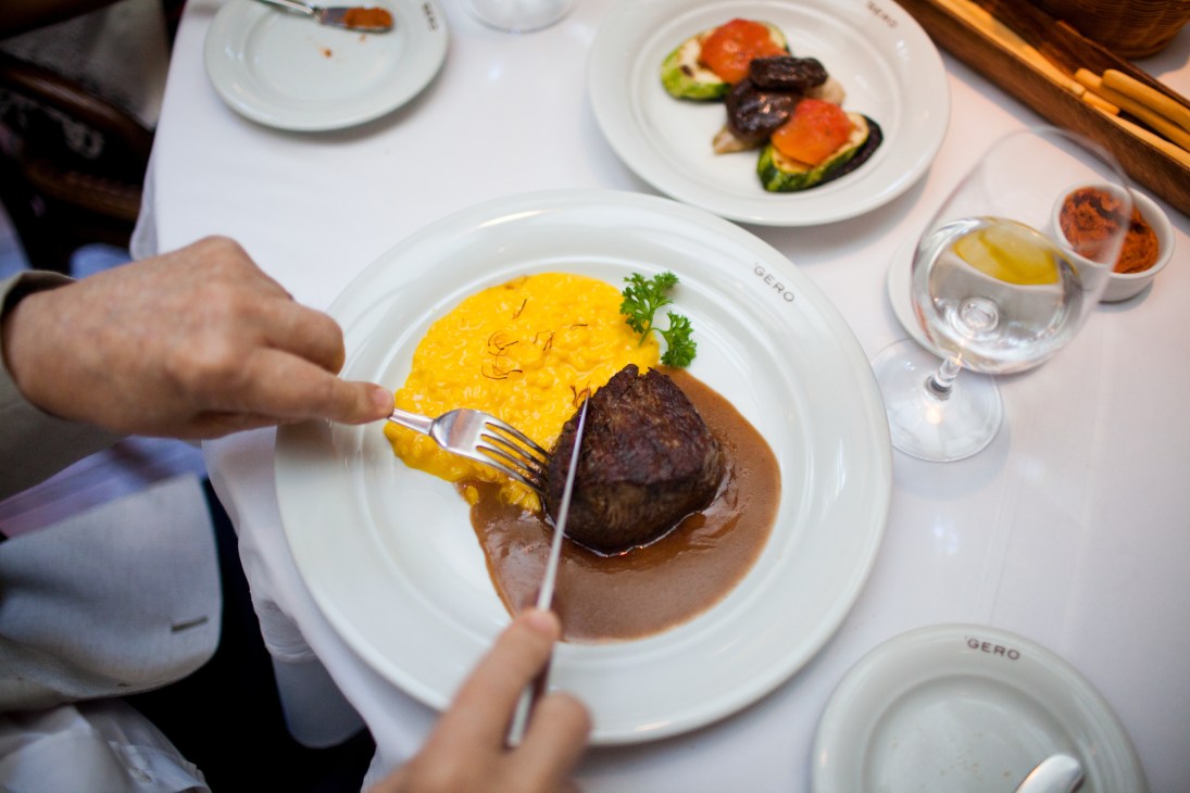 A diner cuts into beef fillet served with saffron risotto and sauce at Gero restaurant.