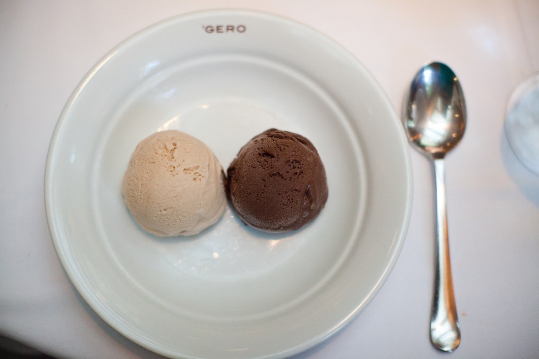 Two scoops of sorbet, one hazelnut and one chocolate, on a white Gero plate with a spoon.