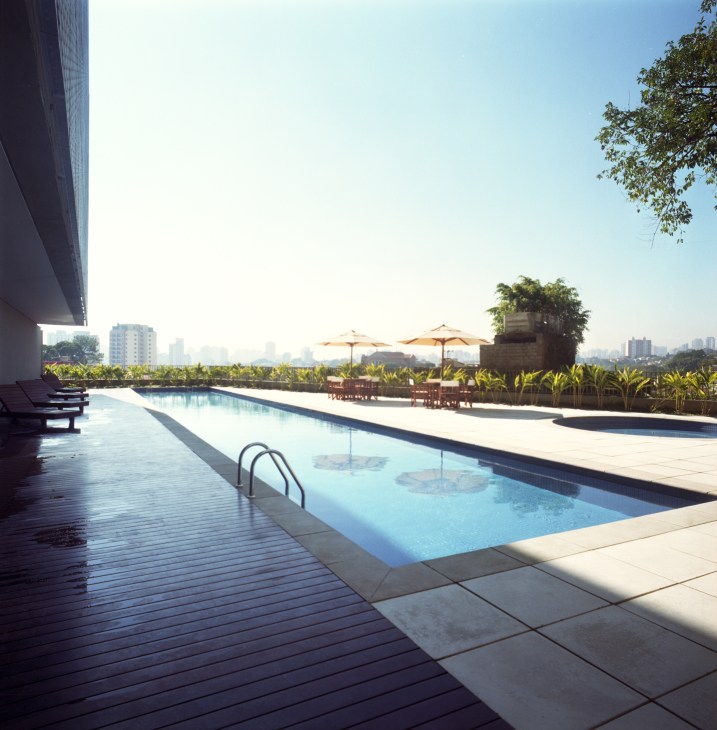 Open-air swimming pool with São Paulo skyline views, umbrellas, and landscaping on the 360º Building rooftop.