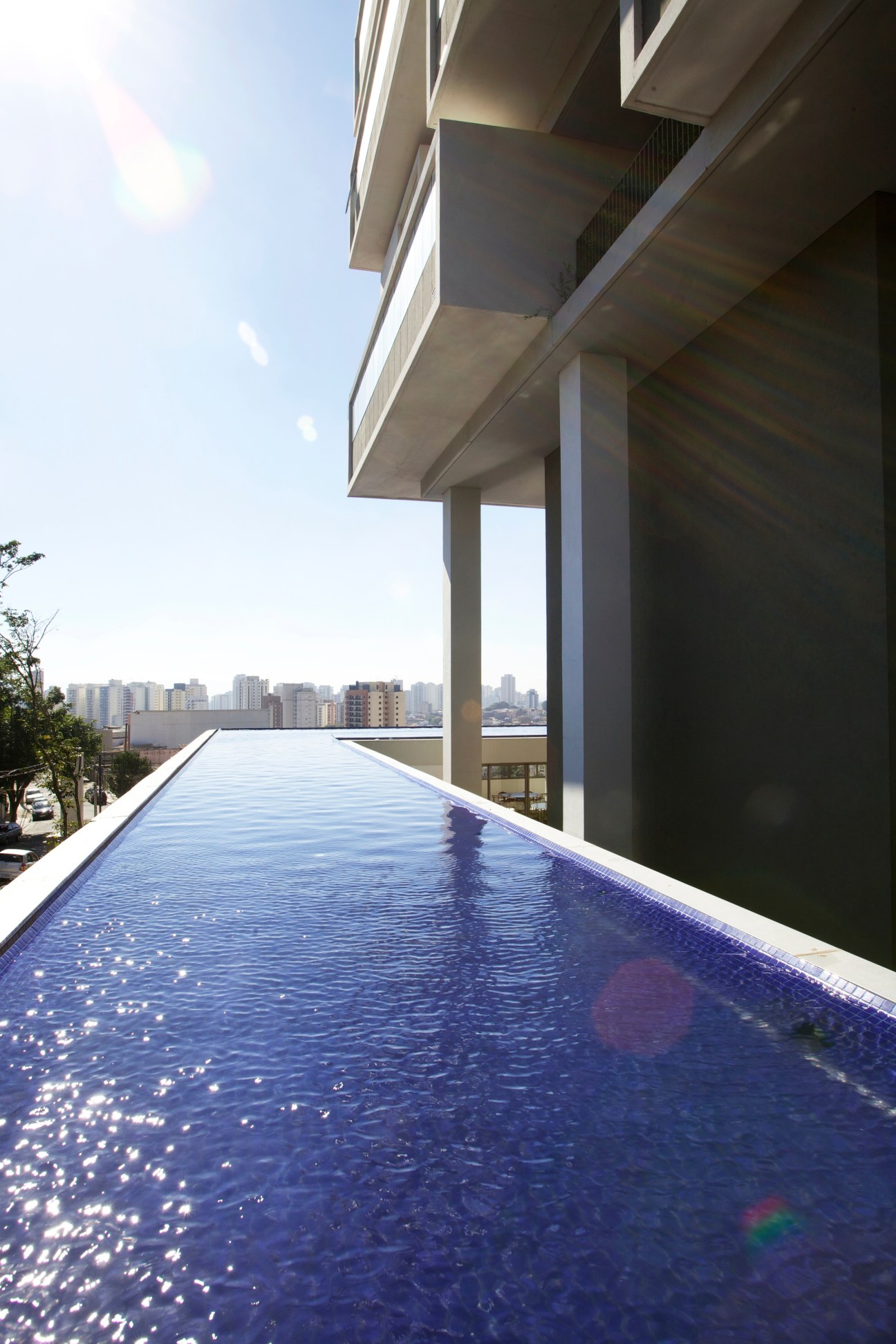 Rooftop pool with São Paulo skyline visible beyond the concrete structure of the 360º Building.