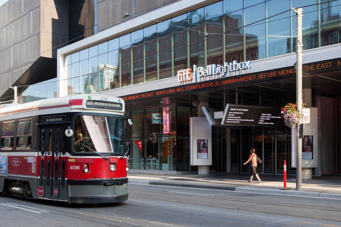TIFF Bell Lightbox cinema entrance with red Toronto streetcar passing by on street.