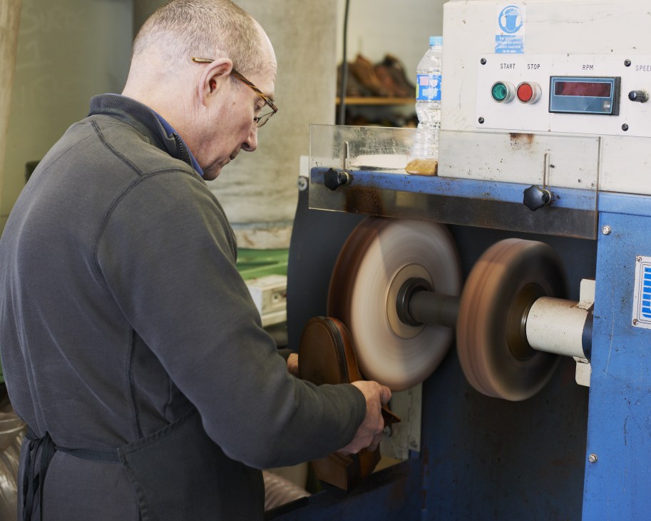 Craftsman operating a leather burnishing machine at Joseph Cheaney & Sons shoemaking factory.